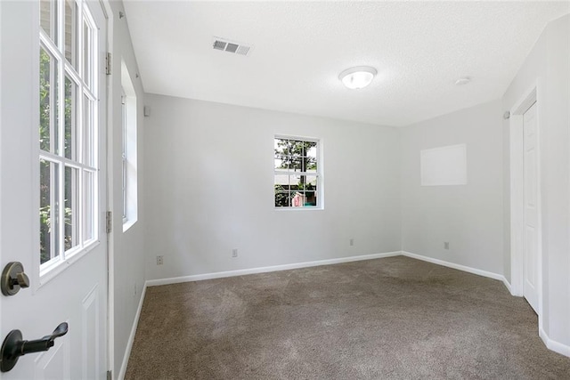 carpeted empty room with visible vents, a textured ceiling, and baseboards