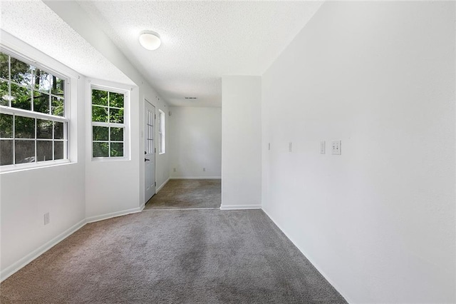 carpeted spare room with a textured ceiling and baseboards