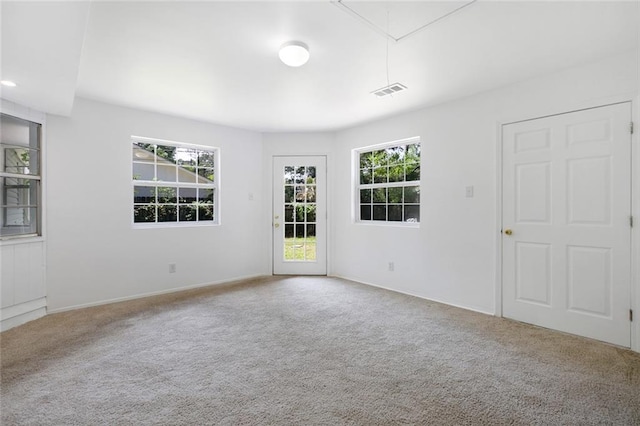 empty room featuring attic access, carpet flooring, and visible vents