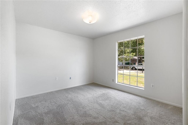 carpeted spare room featuring a textured ceiling and baseboards