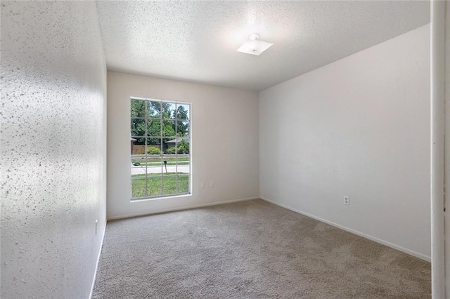 carpeted spare room featuring baseboards and a textured ceiling