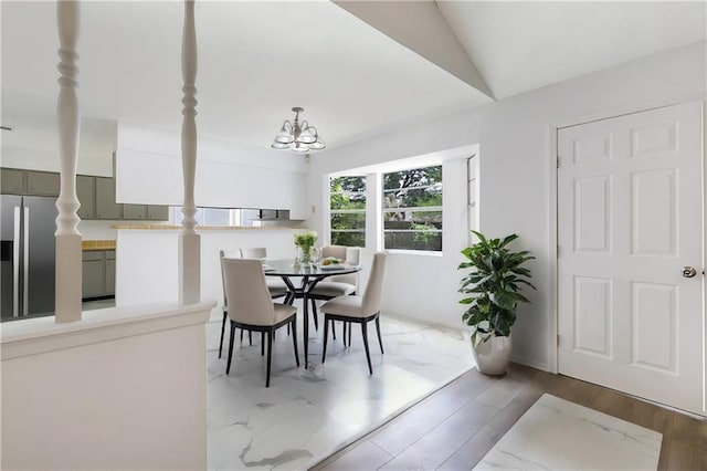dining space with lofted ceiling, light wood-style floors, and a notable chandelier