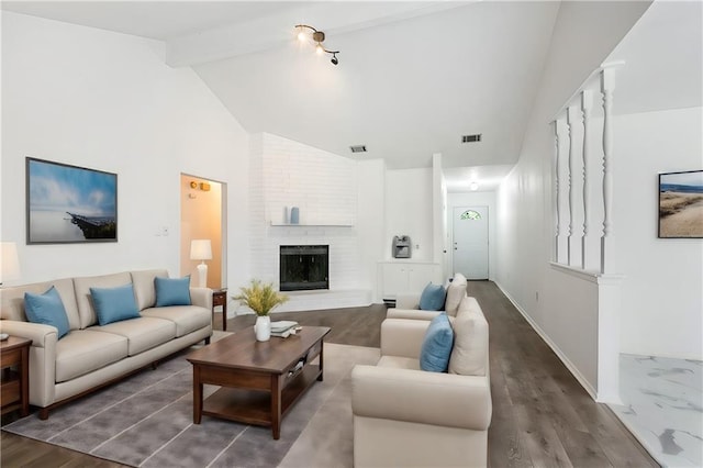 living room with a brick fireplace, visible vents, beamed ceiling, and wood finished floors