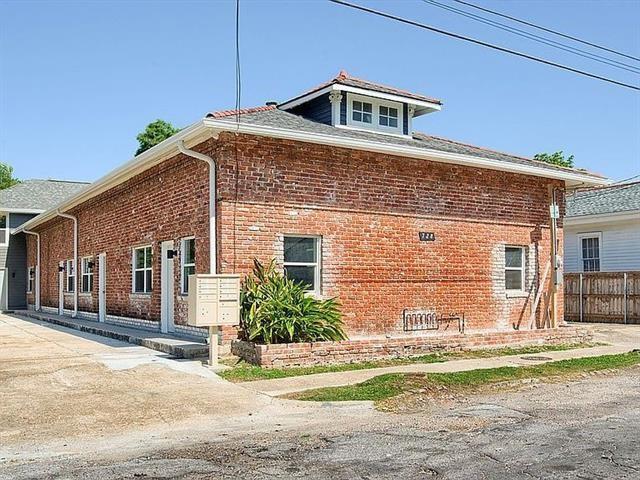 view of property exterior featuring brick siding, driveway, mail area, and fence