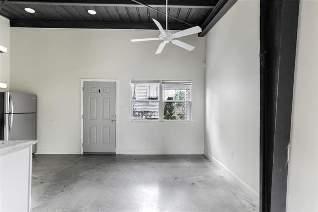 empty room with baseboards, wood ceiling, ceiling fan, beamed ceiling, and concrete floors