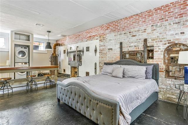 bedroom featuring brick wall, concrete floors, and stacked washing maching and dryer