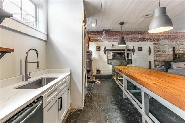 kitchen with a sink, brick wall, stainless steel dishwasher, and decorative light fixtures