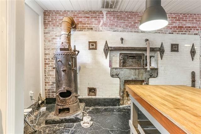 interior space with brick wall and a wood stove