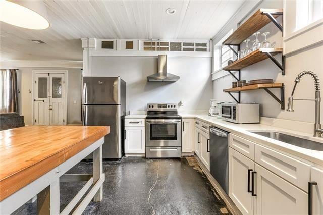 kitchen featuring wall chimney exhaust hood, appliances with stainless steel finishes, light countertops, open shelves, and a sink