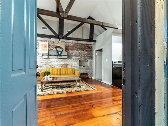 interior space with lofted ceiling with beams, wood finished floors, and visible vents