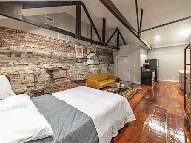 bedroom with baseboards, brick wall, hardwood / wood-style floors, freestanding refrigerator, and high vaulted ceiling