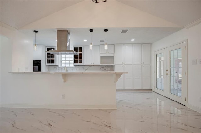 kitchen featuring french doors, marble finish floor, white cabinets, island range hood, and a kitchen bar