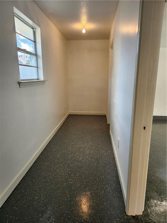 spare room featuring a textured ceiling and baseboards