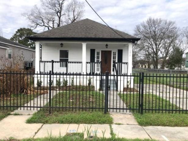 bungalow-style home with a fenced front yard, covered porch, a shingled roof, and a gate