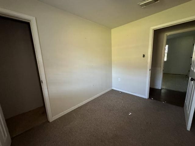 unfurnished bedroom with baseboards, visible vents, and dark carpet