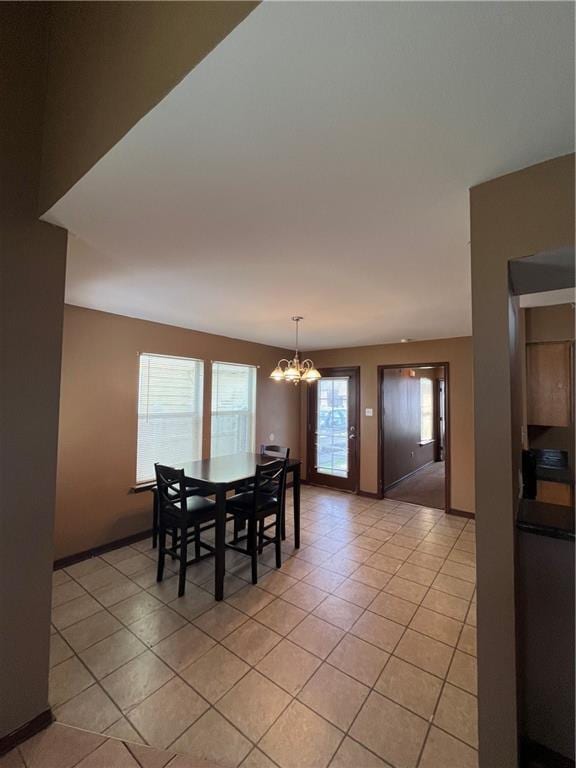 dining area with light tile patterned floors, baseboards, and a chandelier