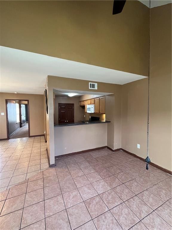 unfurnished living room with light tile patterned floors, visible vents, and baseboards