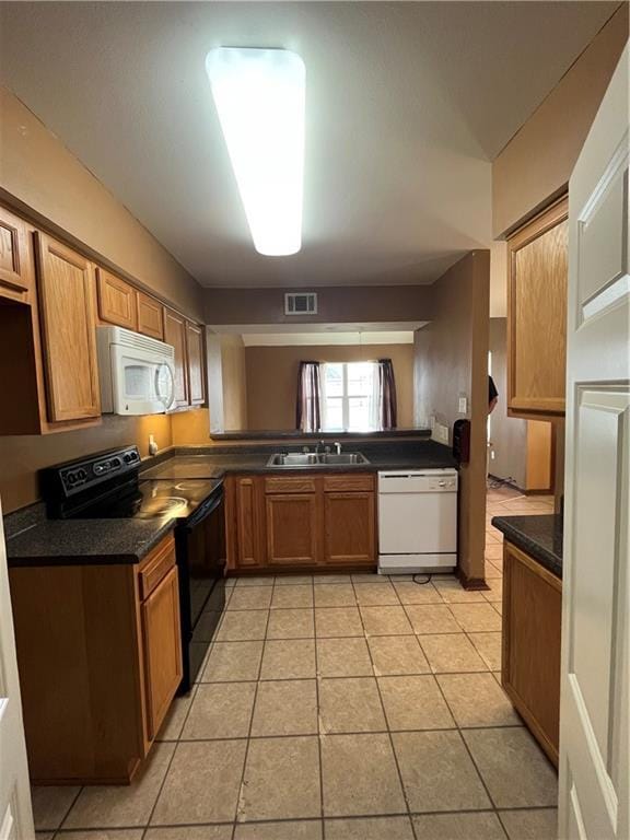 kitchen with white appliances, a sink, visible vents, brown cabinets, and dark countertops