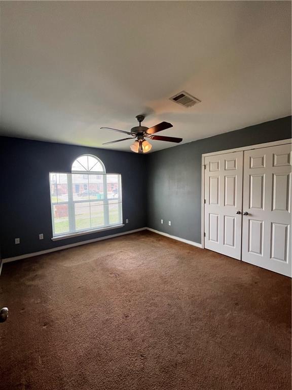 unfurnished bedroom featuring baseboards, visible vents, ceiling fan, carpet flooring, and a closet