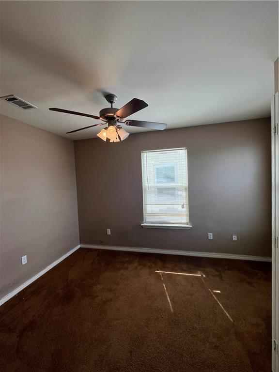 carpeted empty room featuring baseboards, visible vents, and ceiling fan