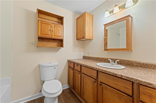 full bath with a textured ceiling, a tub to relax in, toilet, wood finished floors, and vanity