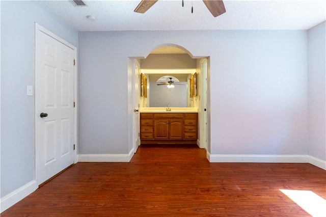 unfurnished bedroom featuring dark wood-style flooring, a sink, and baseboards