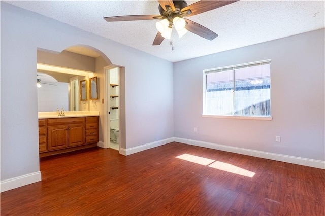 unfurnished bedroom featuring dark wood-style flooring, a sink, a textured ceiling, and baseboards