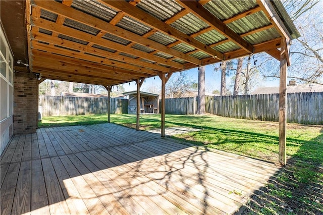 deck with a fenced backyard, an outdoor structure, a lawn, and a shed