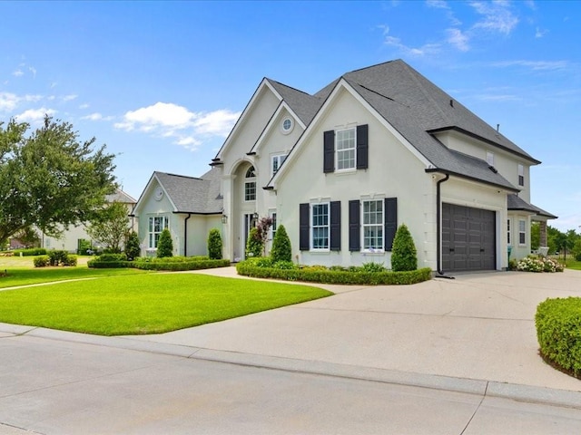 view of front facade with driveway, stucco siding, and a front yard