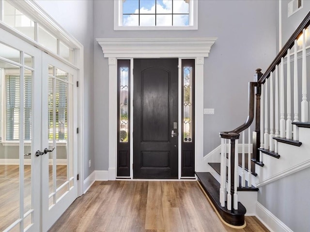 entryway featuring a towering ceiling, a wealth of natural light, visible vents, and wood finished floors