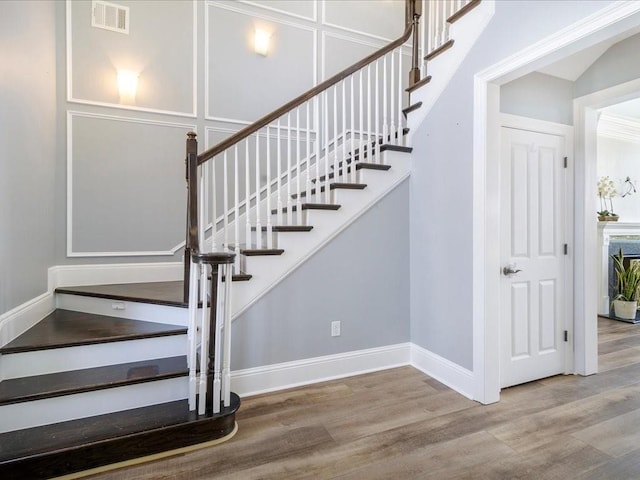 staircase featuring wood finished floors, visible vents, and baseboards