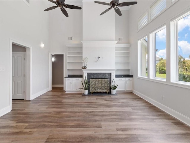 unfurnished living room with light wood finished floors, visible vents, a fireplace, and baseboards