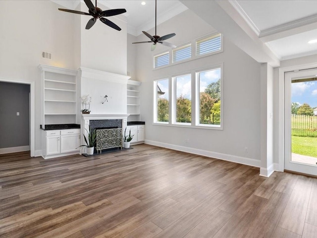 unfurnished living room with dark wood-style flooring, a fireplace with flush hearth, visible vents, baseboards, and ornamental molding