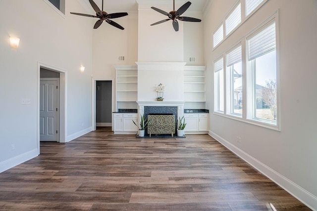 unfurnished living room with dark wood-style floors, a fireplace with raised hearth, visible vents, and baseboards