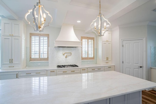 kitchen featuring premium range hood, crown molding, stainless steel gas cooktop, and a notable chandelier