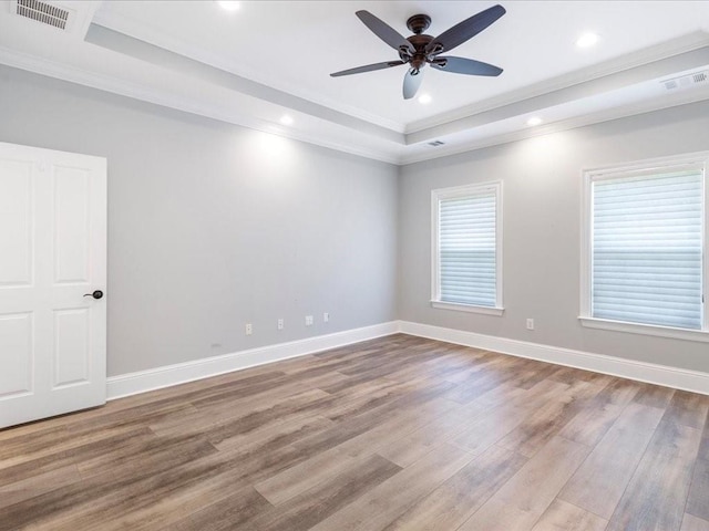 empty room with visible vents, a raised ceiling, and wood finished floors