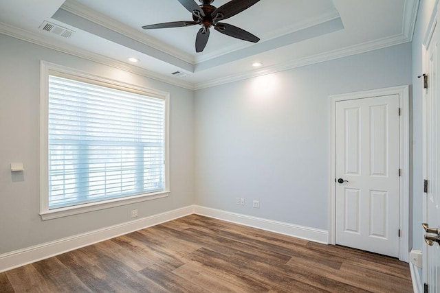 unfurnished room with baseboards, visible vents, a tray ceiling, and wood finished floors