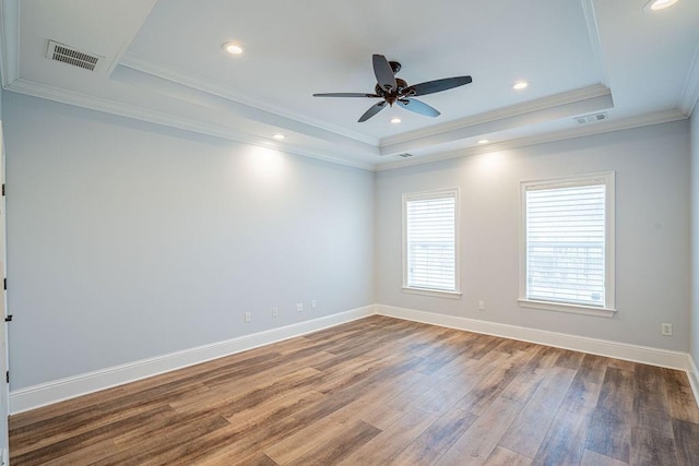 spare room featuring baseboards, visible vents, a raised ceiling, and wood finished floors