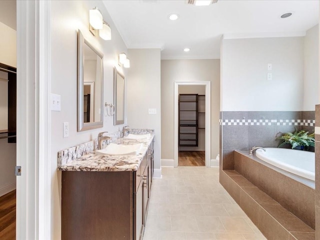 full bathroom with a bath, double vanity, baseboards, and a sink