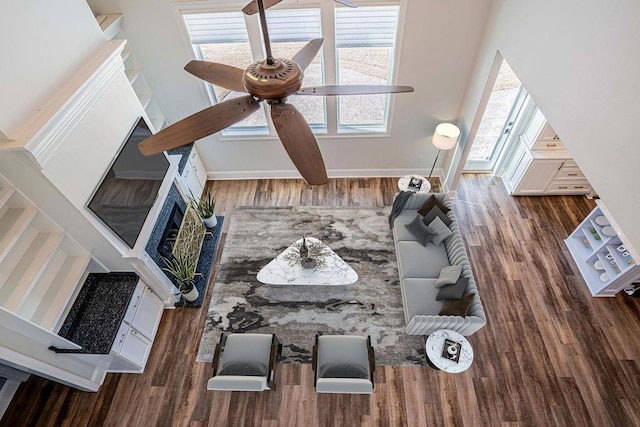 living area featuring ceiling fan, baseboards, and wood finished floors