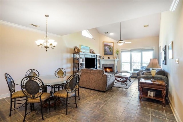 dining room with a warm lit fireplace, baseboards, visible vents, vaulted ceiling, and ceiling fan with notable chandelier