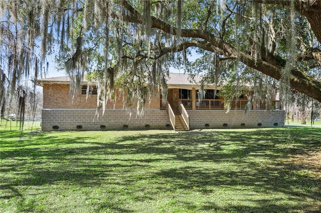 view of front facade with crawl space, brick siding, a front lawn, and stairs