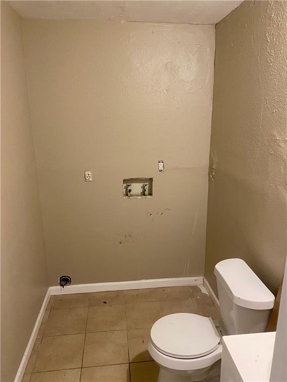 bathroom featuring tile patterned flooring, toilet, and baseboards