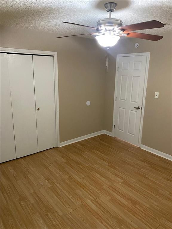 unfurnished bedroom featuring light wood-style floors, a closet, baseboards, and a textured ceiling