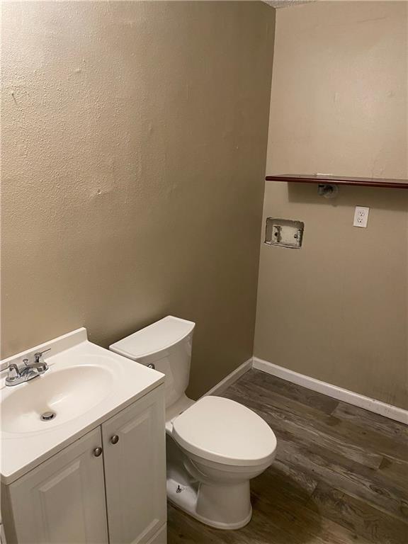 bathroom with toilet, baseboards, wood finished floors, and vanity