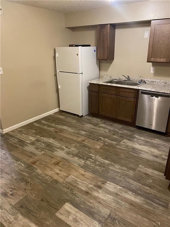 kitchen with dark wood finished floors, freestanding refrigerator, a sink, a textured ceiling, and dishwasher