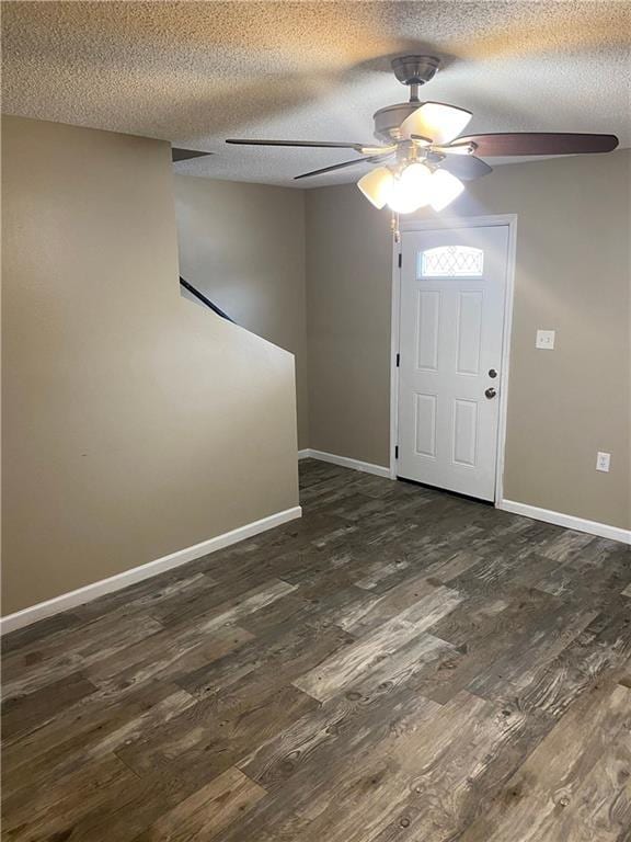 foyer entrance with dark wood-style floors, a ceiling fan, baseboards, and a textured ceiling