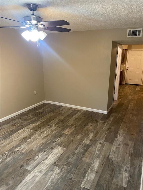 spare room featuring baseboards, visible vents, dark wood finished floors, and a textured ceiling