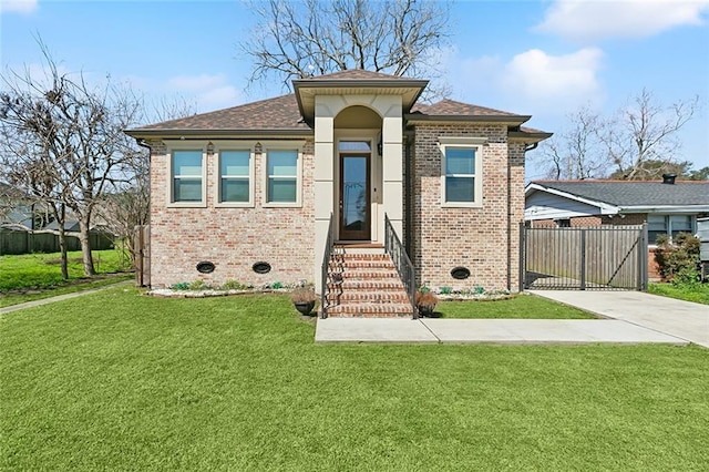 prairie-style home featuring driveway, fence, a front lawn, and brick siding