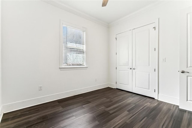 unfurnished bedroom featuring baseboards, dark wood finished floors, ceiling fan, crown molding, and a closet